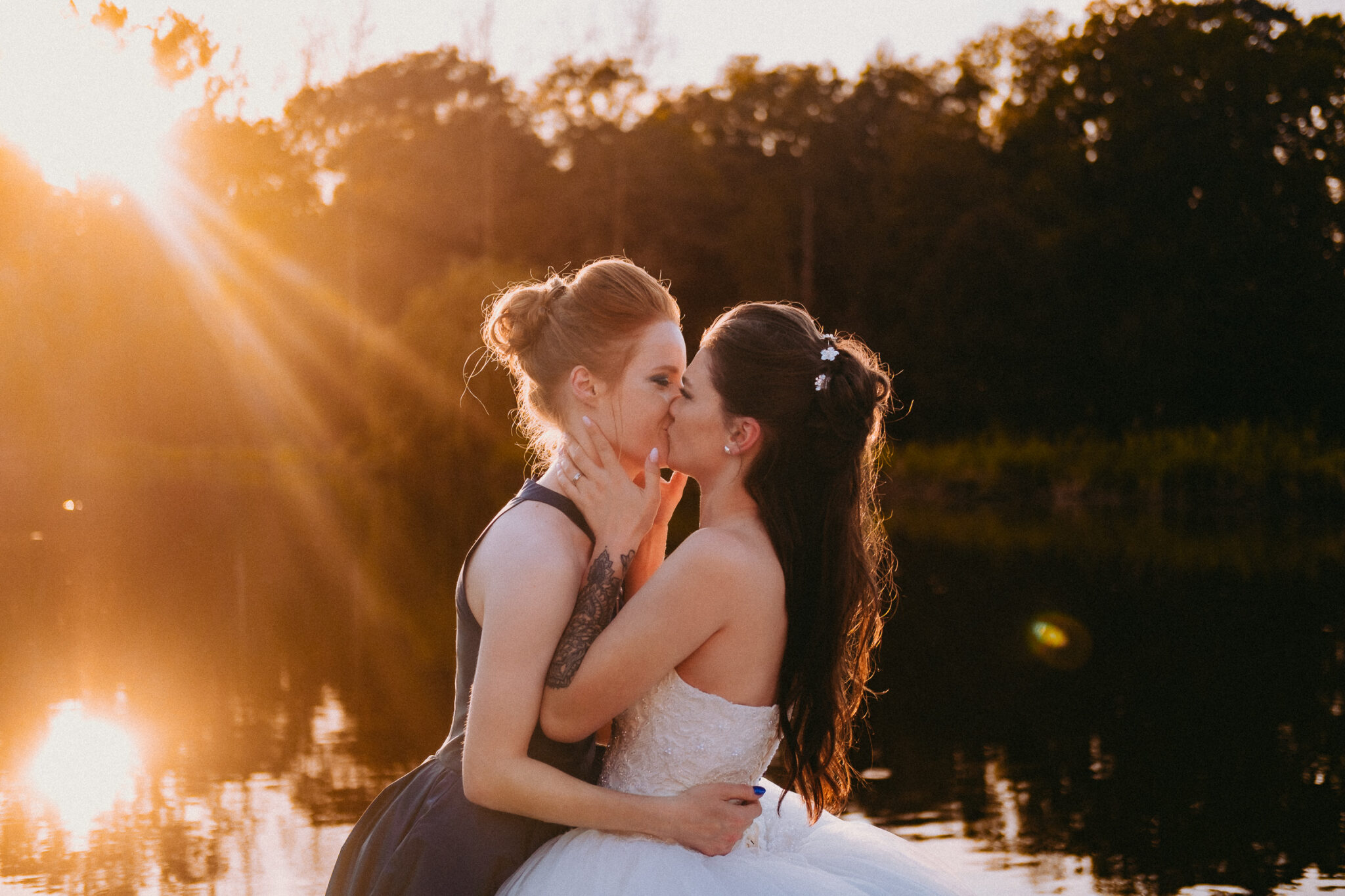 Baiser des mariées au coucher du soleil au bord d'un étang, mariage en Brabant wallon